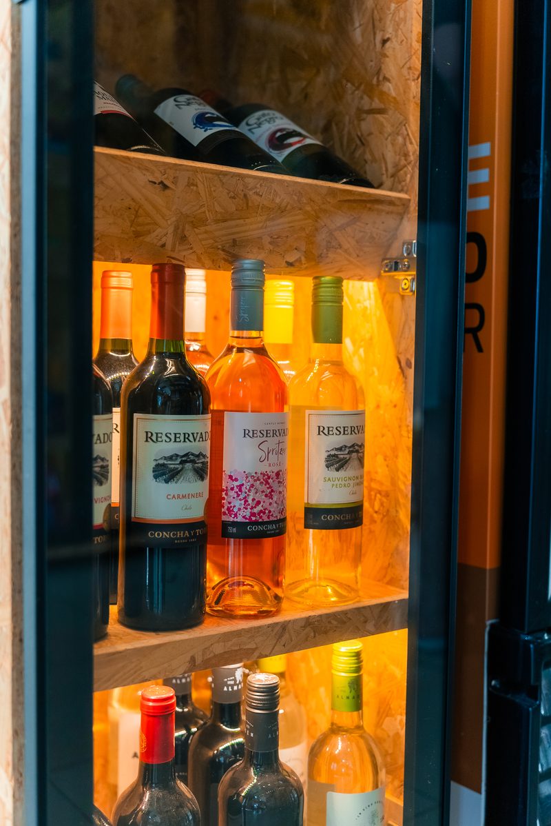 Adega iluminada com garrafas de vinho tinto, branco e rose